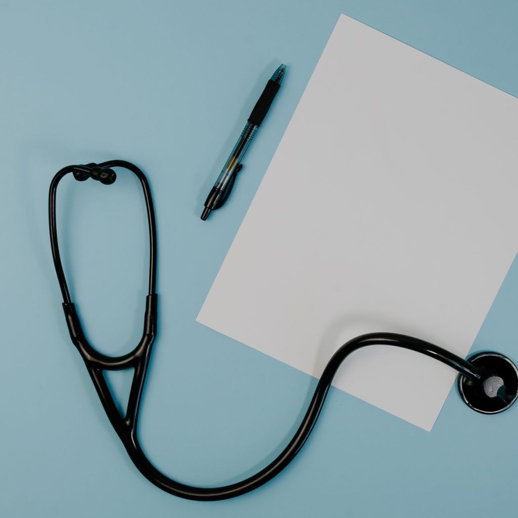 Flat lay of stethoscope, blank paper, and pen on blue surface — Commercial Dumbbells Engineered for Durability and Heavy Use