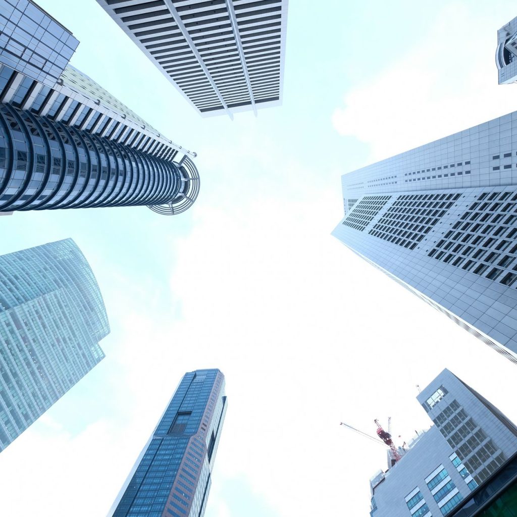 A striking upward view of various skyscrapers in an urban setting against a clear sky. — Green Oasis Unveiled: Journeying Thr