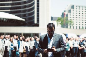 Focused businessman using tablet in a bustling crowd in Toronto's busy urban setting. — Navigate Medicare with Confidence Usi