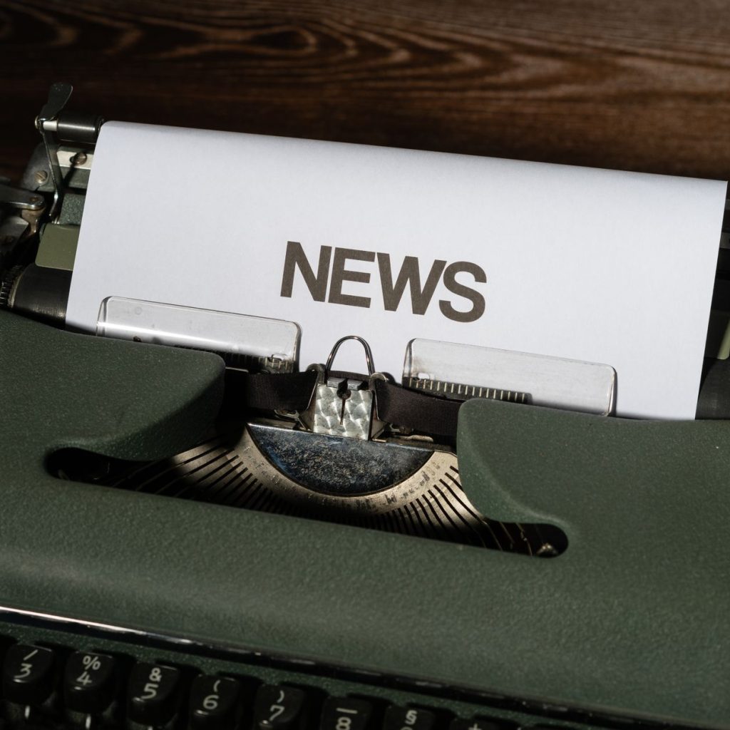 A retro typewriter featuring a 'NEWS' headline typed on white paper against a wooden surface. — Rang lista casina