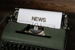 A retro typewriter featuring a 'NEWS' headline typed on white paper against a wooden surface. — Rang lista casina